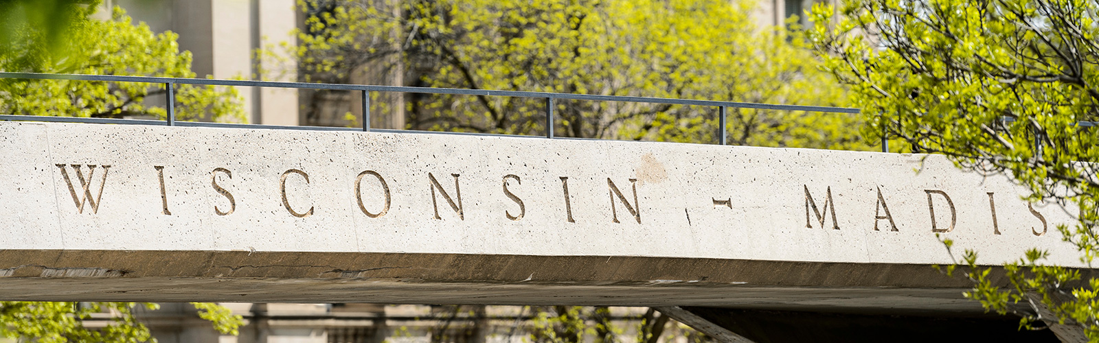 Concrete bridge with "Wisconsin-Madison" on it and trees behind.