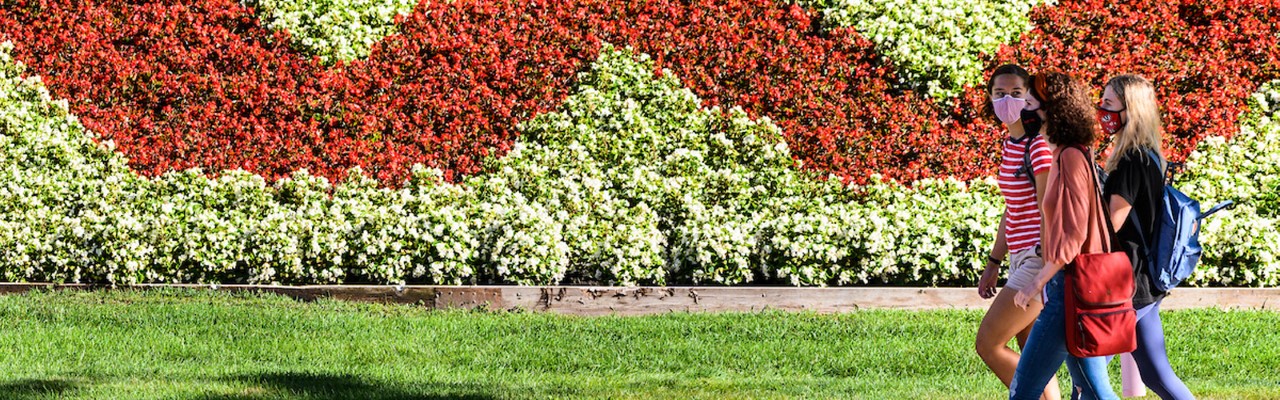 Students walk in front of flowers in a W shaped planting