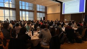 Students at tables listen to presenter