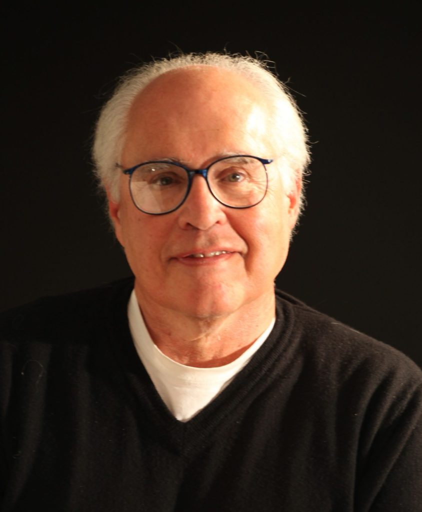 Ellis in a brown sweater in front of a black background.