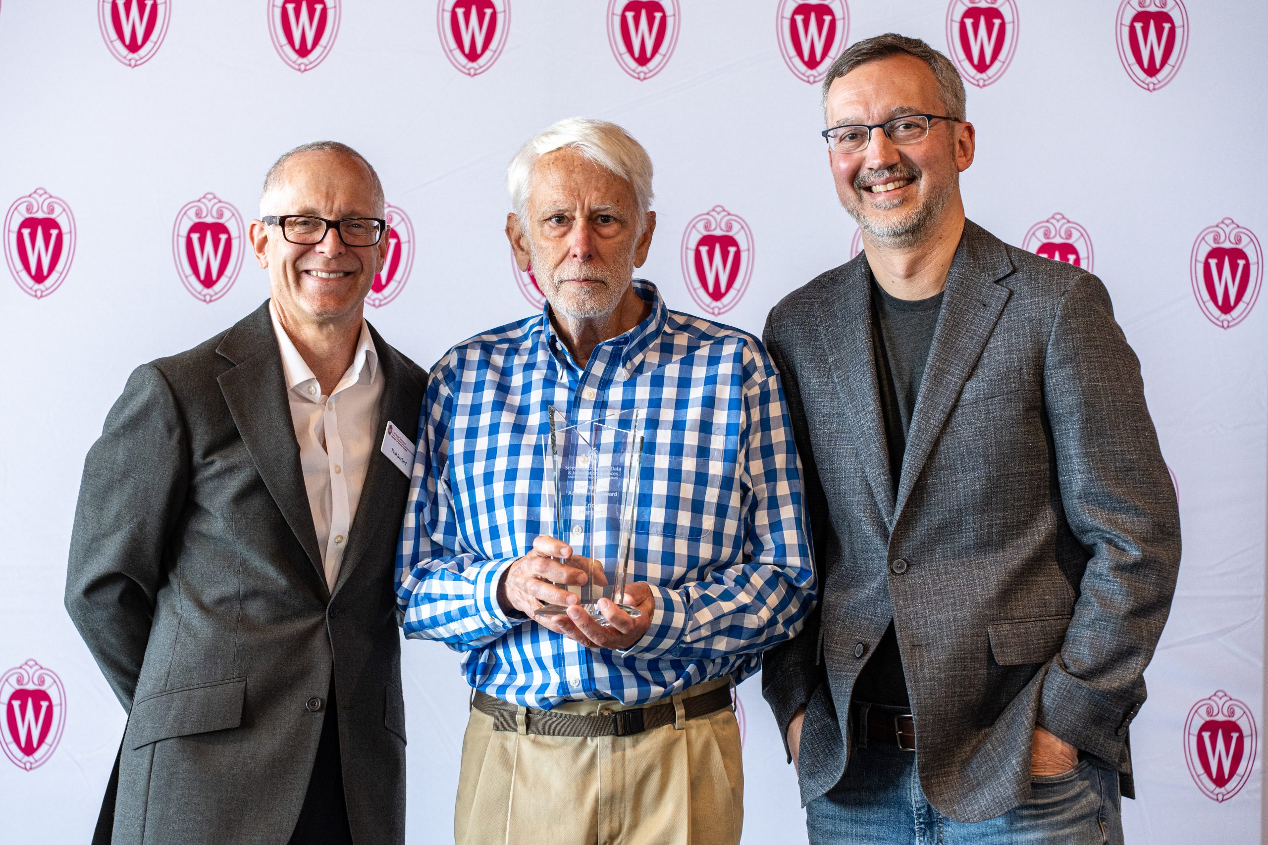 Computer Sciences Chair Paul Barford, alumnus Eric Harslem MS'68, and Professor Remzi Arpaci-Dusseau pose as Harslem receives 2026 Distinguished Achievement Award.