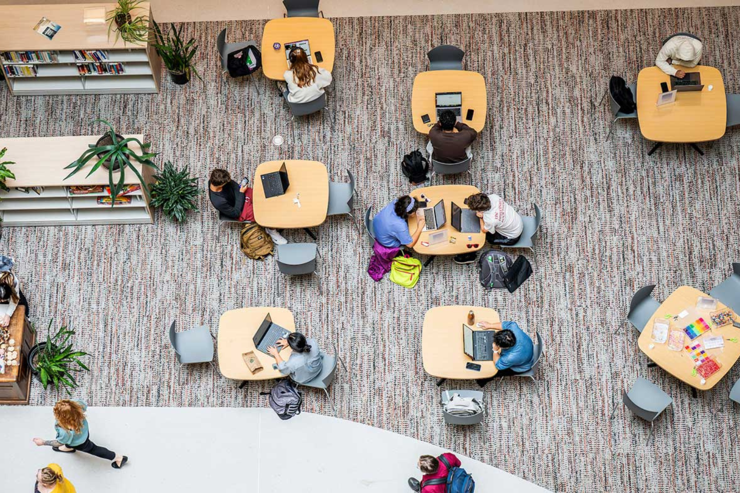 Students working at tables on laptops, seen from above