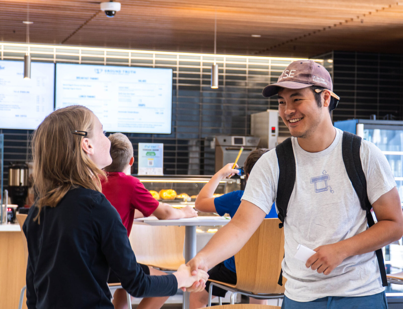 Education graduate student Ryan shakes the hand of a middle schooler.