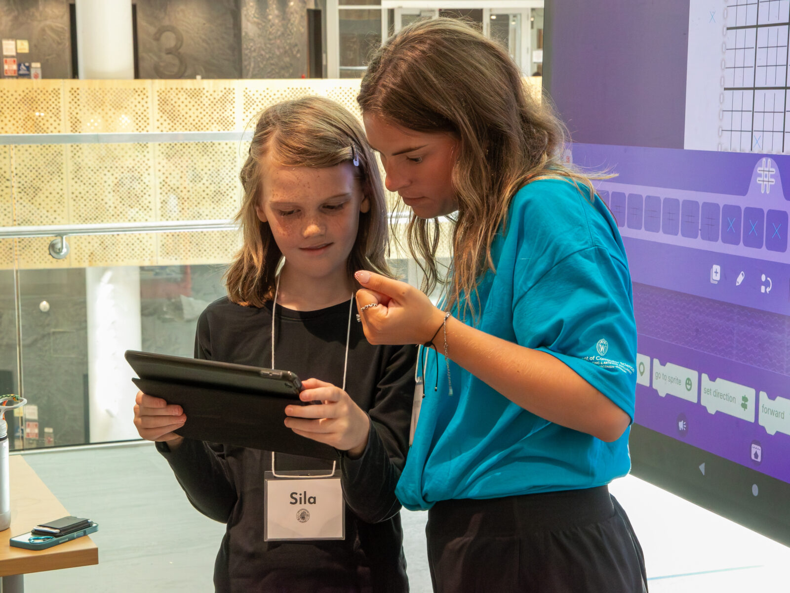 Two people stand together looking at a tablet.